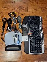 Full view of keyboard, mouse, mouse pad, and cables arranged on a wooden floor