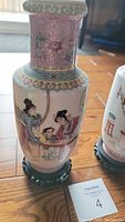 Front and side view of one Chinese porcelain vase with figures and floral motifs, on wooden stand.