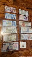 All eleven bank notes arranged on wooden floor in protective sleeves.