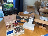 Overview photo showing multiple jewelry boxes and loose costume jewelry items on a wooden table.
