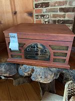 Closed view of wooden 5-in-1 entertainment center with visible speaker mesh and control panel on front.