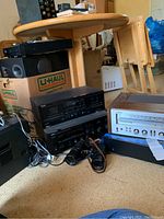 View of multiple electronics on the floor including Sony DVD/CD player, receiver, TEAC cassette player, and speakers with cables visible