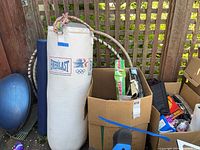 Wide shot showing Everlast punching bag, exercise ball, foam roller, hula hoop, and two boxes with games and other items.