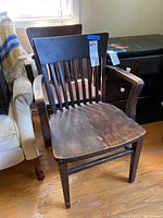 Two vintage wooden office chairs side by side showing their worn seats and slatted backs.