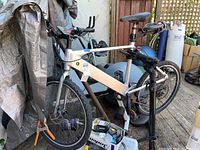 Front view of silver GenZe e101 electric bicycle mounted on black rear-wheel trainer and orange front-wheel block