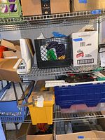 Shelf with cardboard boxes, plastic bins, power tools and hardware supplies.