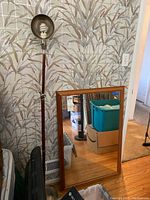 Mirror leaning against wall next to an adjustable floor lamp with a metal shade.