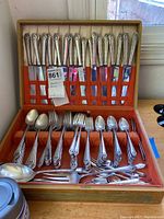 Full view of the 100-piece Holmes & Edwards stainless steel serving utensils set arranged neatly in a wooden box with an orange fabric lining.