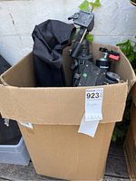 Box filled with several black adjustable tripods and carrying case showed from above.