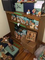 Front view of solid pine bookshelf with various collectible figurines on and around it, showing bookshelf shelves and wood texture clearly.
