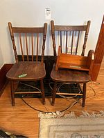 Pair of two child-sized wooden chairs with slat backs and spindle legs. Worn surfaces and finish. Small wooden shelf shown on one chair not included.