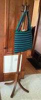 Full view of the coat tree with the striped fabric tote bag hanging from one of the hooks, showing condition and overall appearance.