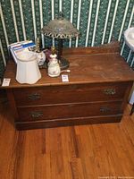Front and top view of the solid wood dresser showing the two drawers with metal handles, flat top surface with some items placed but not included, and the tall backboard.