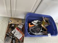 Blue plastic tote filled with household items including an orange Monster hand vacuum, Black & Decker iron, and assorted small boxes