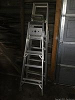 Two aluminum step ladders standing side by side, one taller at about 6 feet and one shorter at 5 feet, showing the overall size and condition.