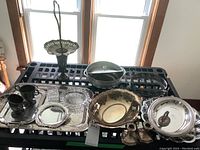 Overview of assorted metal and glass dishes including trays, candleholders, bowl, and covered dish