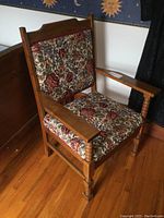 Solid oak armchair with floral upholstery, side view showing armrest design and seat.