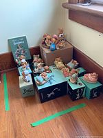 Wide view showing 12 hand painted PenDelfin animal figurines arranged on and around original boxes with one standing booklet titled Barney.
