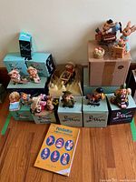 Photo shows the full collection including figurines on boxes, two stacked large boxes, and the PenDelfin Collectors Handbook in front.