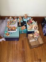 Overall view of twelve PenDelfin animal figurines arranged on boxes and floor, featuring rabbits and a dog in playful poses.