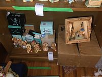 Photo showing a shelf with six PenDelfin animal figure collectibles, with some original boxes, and a framed diorama placed on cardboard boxes next to them.