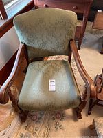 Full view of the upholstered rocking chair showing green patterned fabric on seat and back, wooden arms, and legs.