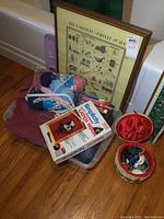 Overall lot showing framed print, yarn skeins, knitting needles, pattern booklets and basket.