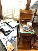 Photo showing wooden table with drawer, wooden shelf, small dish, and decorative items on top