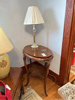 Full view of wooden oval table with lamp and shade on top