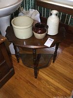 Wooden end table with three stoneware pots displayed on top, showing table and pottery items from front angle.