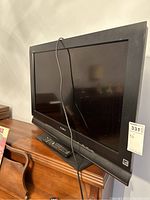 Sony 32 inch TV with a black bezel, placed on wooden surface with remote visible beneath the screen.