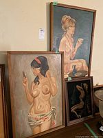 Framed paintings showing two female nude portraits and one partially visible.