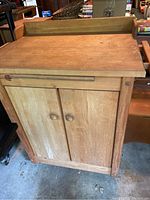 Front view of wooden kitchen island cart with butcher block top and cabinet doors underneath.