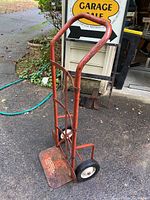 Full view of red metal Craftsman hand truck with curved handle, two wheels, and rectangular base plate showing wear and rust.