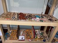 Two-tier shelving unit with full assortment of necklaces, earrings, pins and rings visible across two levels