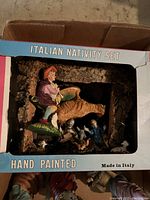Boxed Italian hand painted nativity set with visible cat figure and multiple smaller figurines inside.