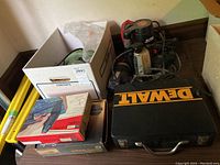 Overview of power tools including DeWalt drill case, box with supplies, Rockwell saw visible.