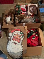 Boxed vintage Christmas ornaments and decorations including a cardboard Santa face cutout and assorted ornaments in boxes