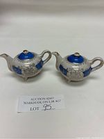 Pair of blue and white teapot-shaped salt and pepper shakers with gold accents and intricate silver detailing