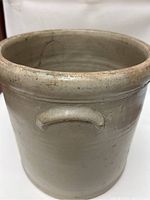Top half of the crock showing off-white glaze and crack inside near rim.