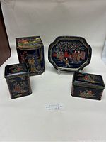 Four metal tins with Japanese style artwork set against a light background, showing different angles and details of designs.