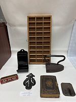 Front view of the lot showing all multiple items including wooden organizer, cast iron, photo album, receipt holder, Oxo tin and decorative metal piece.