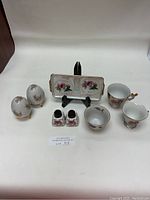 Overview photo showing entire set including salt & pepper shakers, rose set, lusterware tray, demitasse cups and sake cup on display stand.