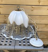 Blown glass pendant chandelier showing white opaque top melting into clear glass bottom with wavy rim. Attached chain and ceiling mount included.