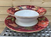 View of ceramic serving bowl placed on top of matching large serving plate, showing decoration and dimensions