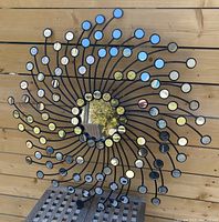 Full front view of the black metal sunburst wall decor featuring many small circular mirrors and a central round mirror showing reflections.