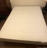 Full view of queen size mattress with beige cover and stitching detail