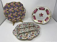 Overall view showing three vintage ceramic plates: Hazel chintz plate, rose plate, and Old Cottage Chintz divided dish.