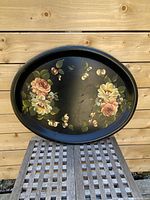 Full view of the oval black metal tray with floral hand-painted decoration.