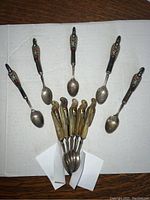 Full view of 10 spoons arranged showing inlaid horn and bone handles carved and painted as Hud Hud Hoopoe birds.